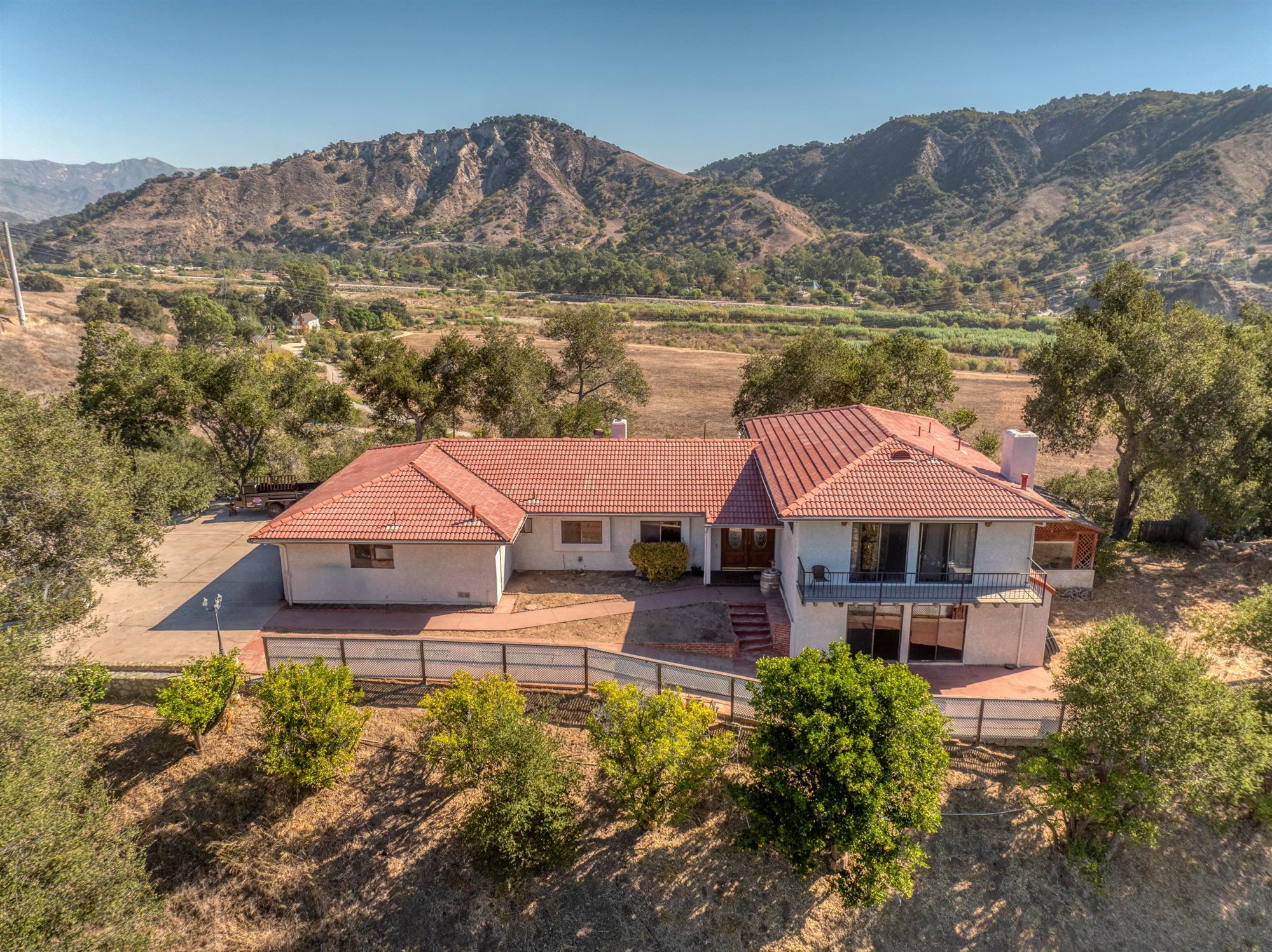 Aerial view of 8257 Camp Chaffee Rd with its tile roof, surrounding trees and mountain backdrop